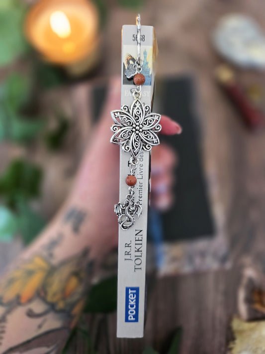 marque-page en métal en forme de petit dragon avec une grande fleur ciselé au dessus. Deux pierres naturelles de sable doré est sur le signet. Un bijou de livre original. Un cadeau pour lecteur de fantasy. Romantasy. Bellette Workshop. dans la tranche d'un livre de tolkien