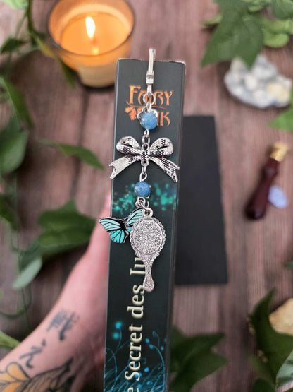 marque-page miroir enchanté, papillon bleu avec un ruban et deux pierres naturelles d'apatite bleue. Le signet est fait à la main par bellette workshop. Ce bijou de lecture est personnalisable. vu de dos montrant le dos du miroir